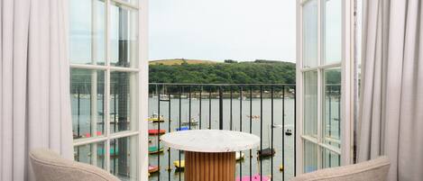 Un balcón con vista a barcos en el agua, una mesa y sillas.