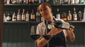 Un cantinero sirviendo una bebida en dos copas de vino.