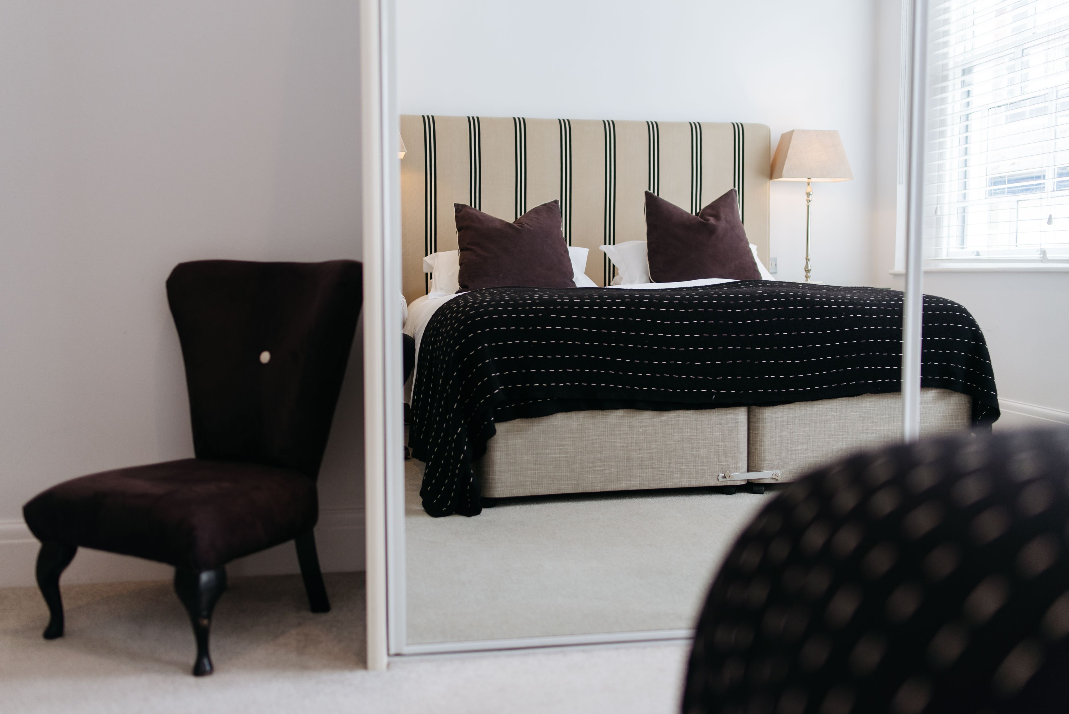 A bedroom with a bed, a chair, a lamp, and a window.