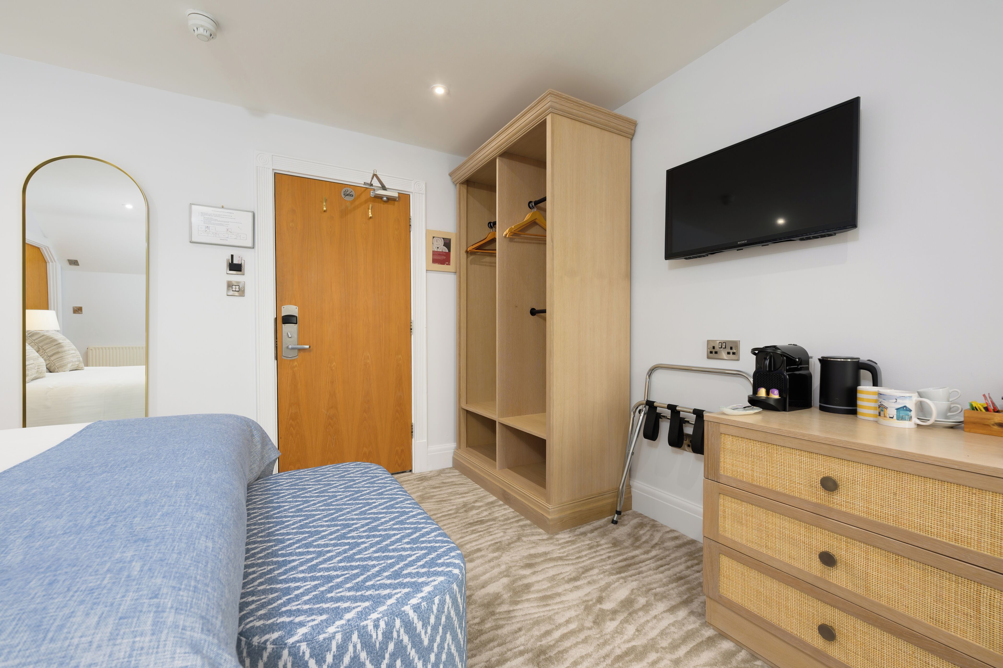 A hotel room with a bed, a wardrobe, a television, and a coffee station.