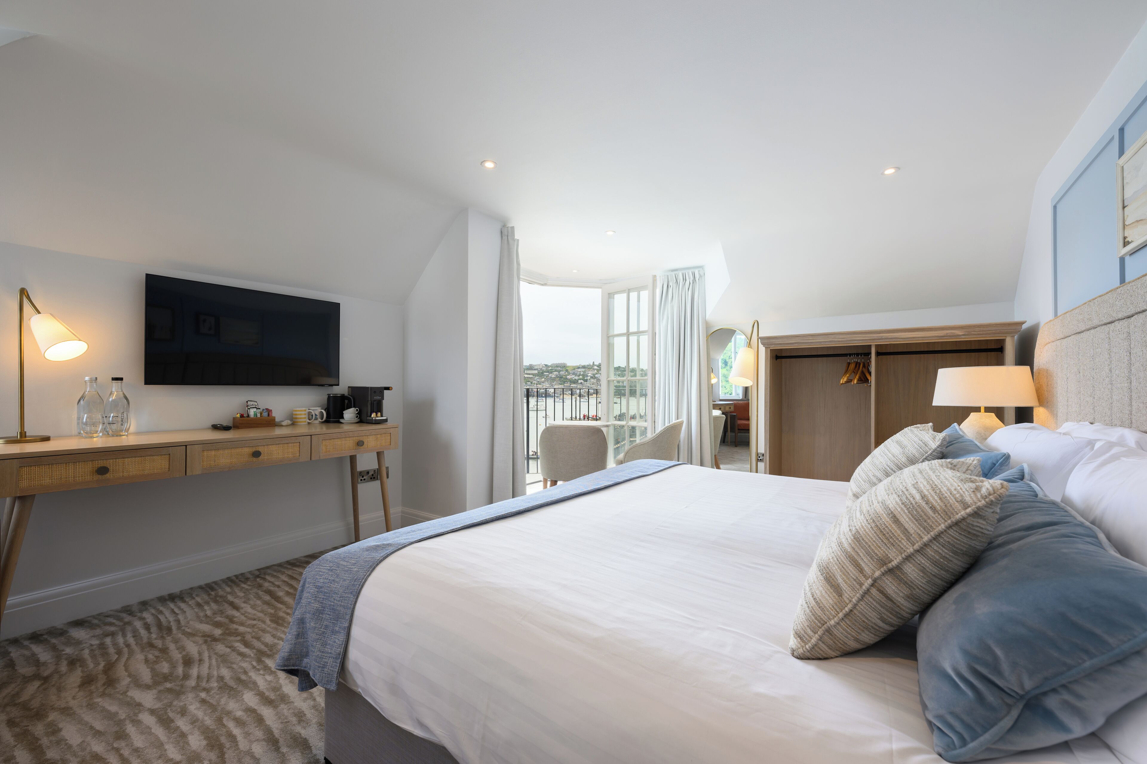Una habitación de hotel con cama, escritorio, televisión y vistas a la ciudad.