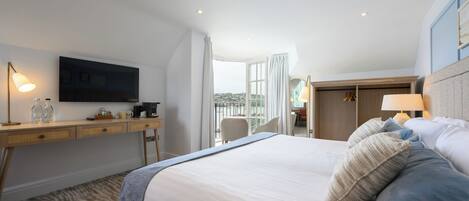 Una habitación de hotel con cama, escritorio, televisión y vistas a la ciudad.