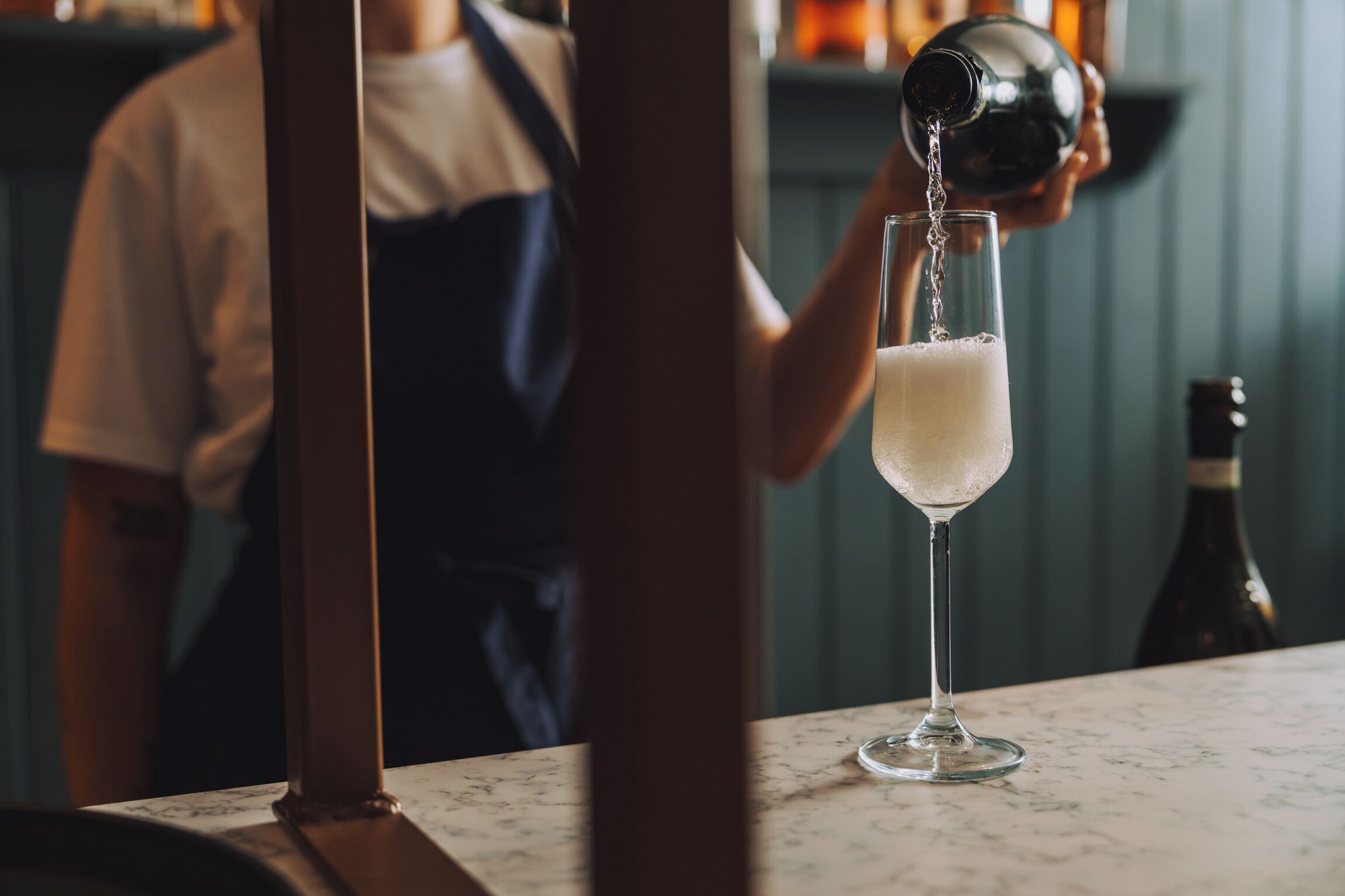 A bartender pouring a drink into a glass.