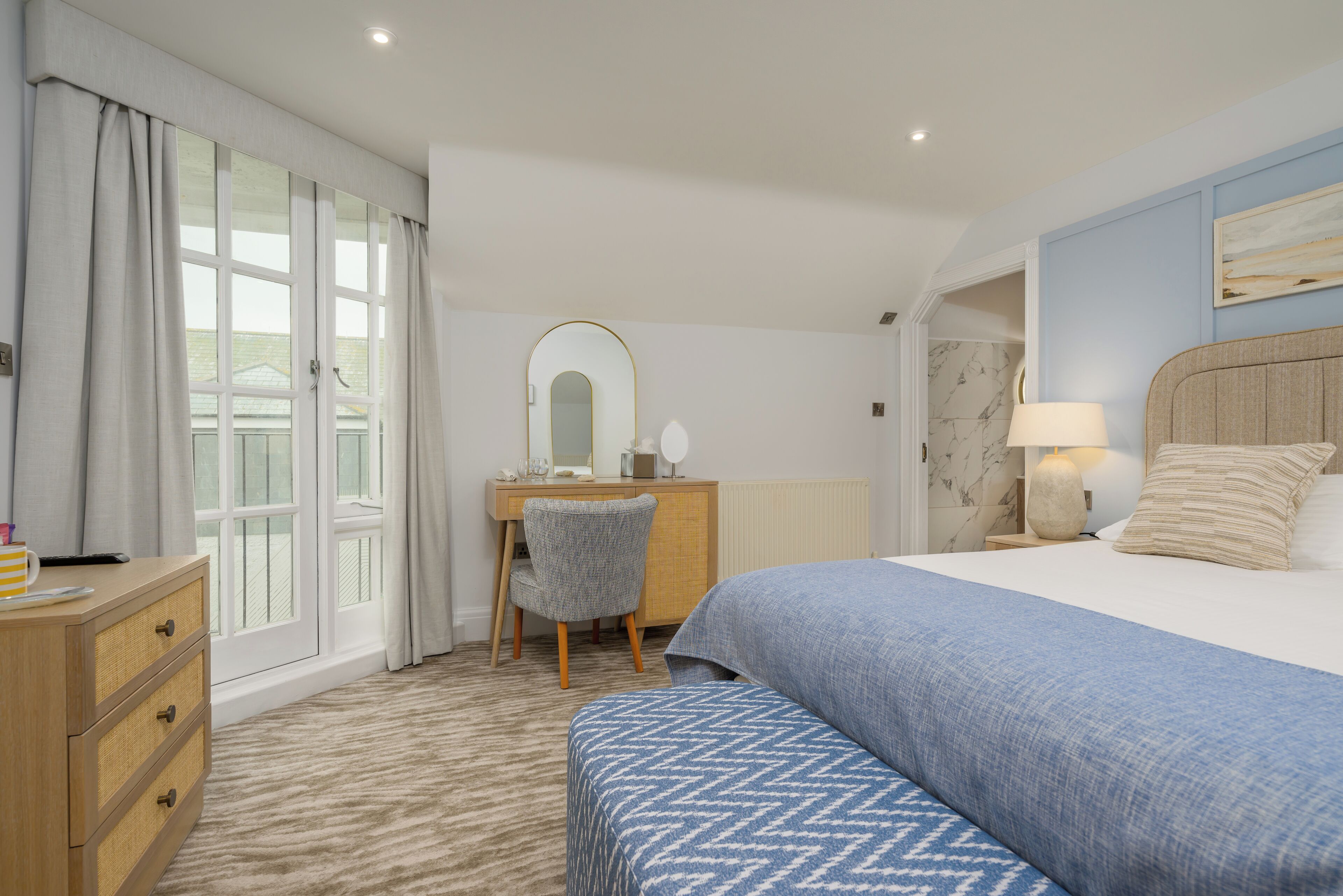 Une chambre d’hôtel avec un lit, un bureau, une chaise et une commode.