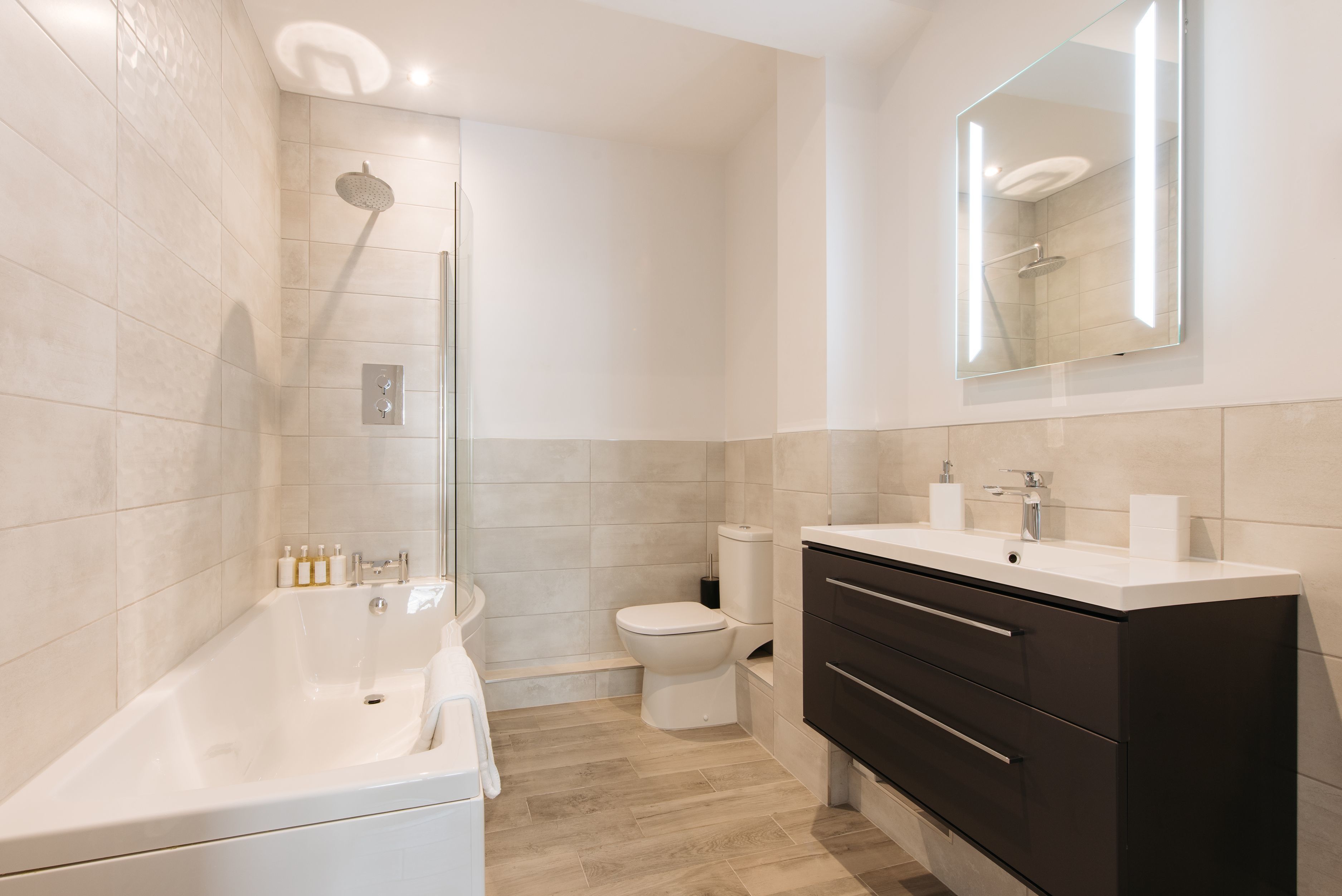 A modern bathroom with a bathtub, toilet, and vanity.