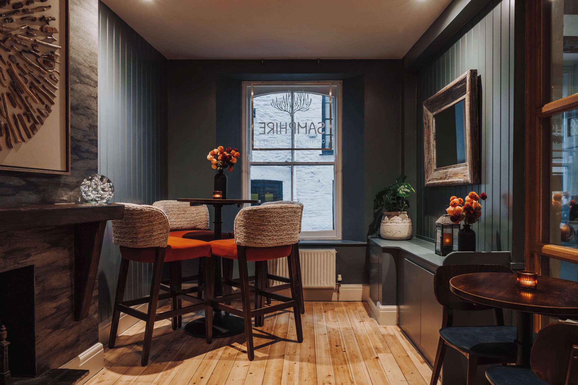 A bar area with wooden stools, a small table, and a window with a view.