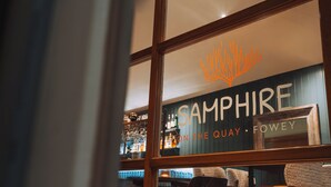 Un bar con un letrero que dice "Sapphire on the Quay - Fowey" y mobiliario de madera.