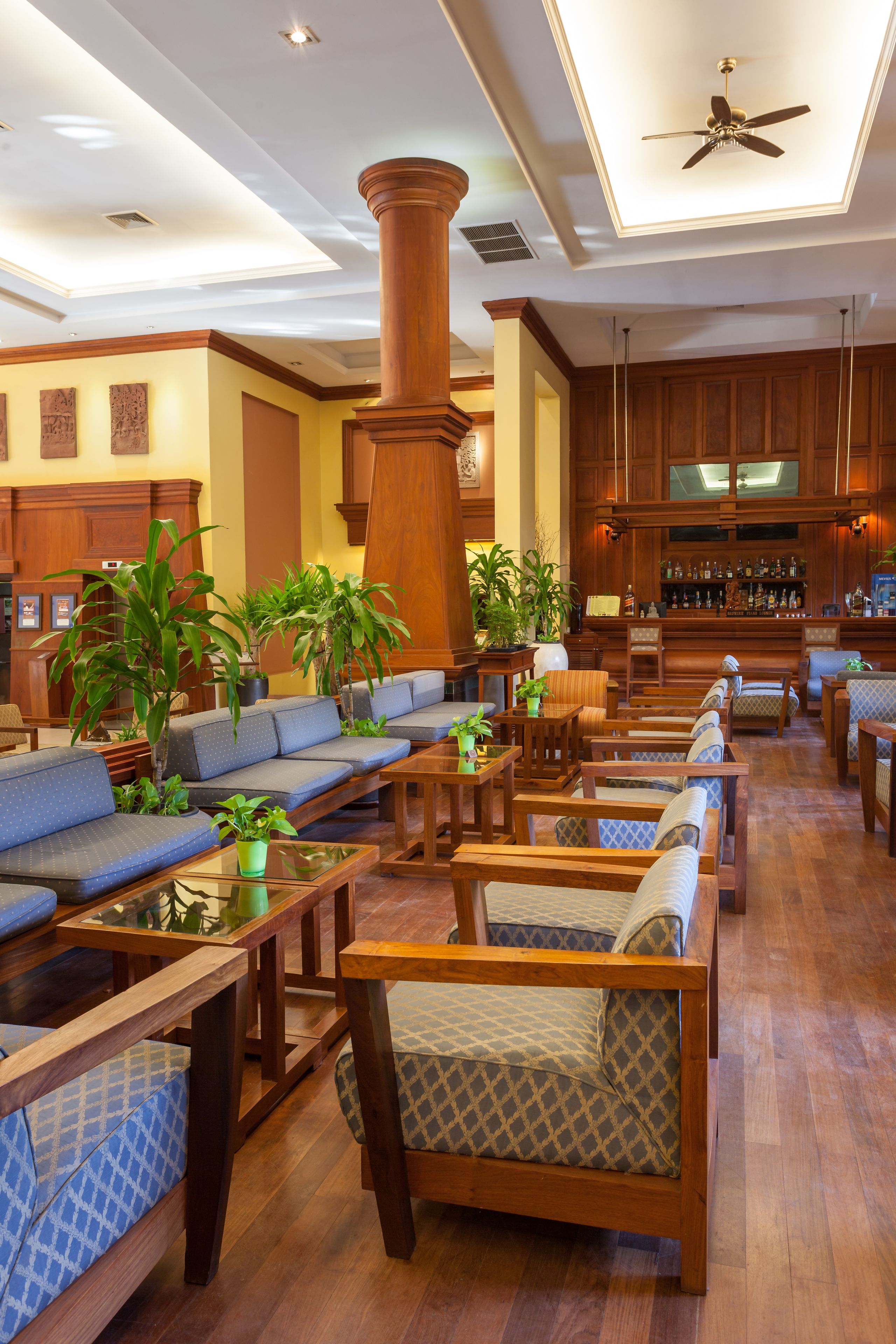 A spacious lobby with wooden furniture, a large pillar, and a bar area.