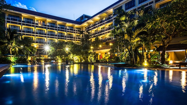 Un hotel con piscina rodeado de exuberante vegetación y múltiples balcones.