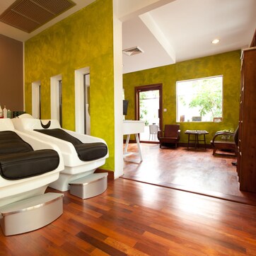 A spa room with two massage chairs, a painting on the wall, and a window with a view of the outdoors.