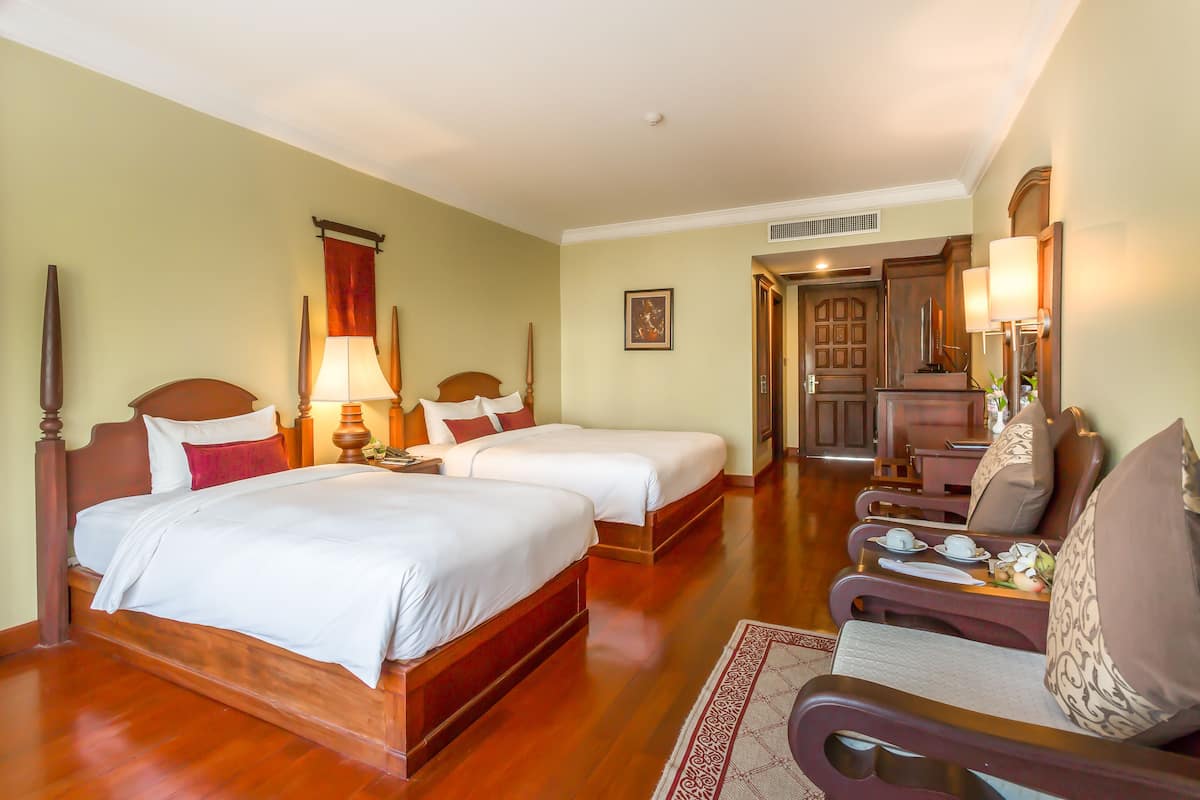 Una camera d'albergo con due letti, un angolo salotto con tavolo e sedie, e una angolo cottura sullo sfondo.