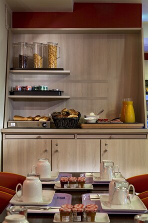 A breakfast setup with a coffee maker, teapot, and various breakfast items on a table. - Timhotel Odessa Montparnasse (Paris)