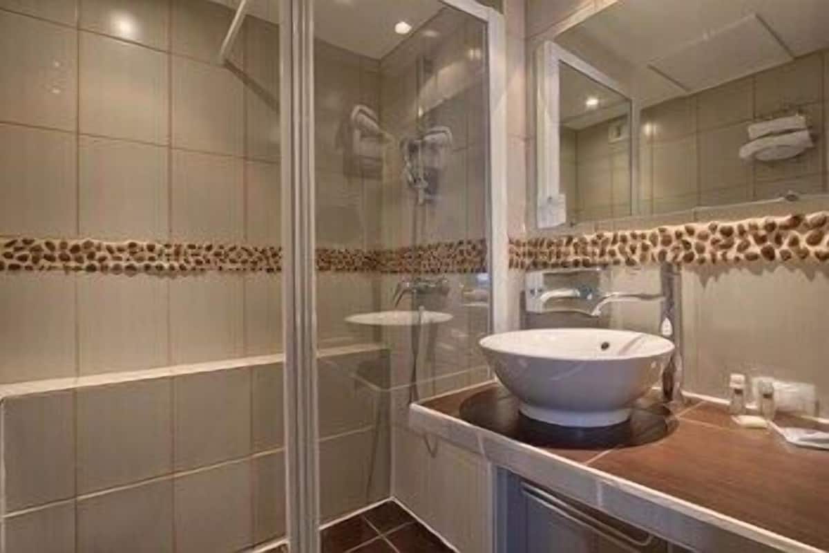 Un bagno con box doccia in vetro, un lavandino bianco e una bordura con motivo leopardato al muro.