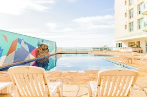 Una piscina al aire libre, sombrillas, sillones reclinables de piscina