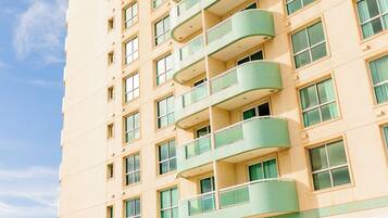 A high-rise hotel with multiple balconies, a pool area with lounge chairs, and a bar.
