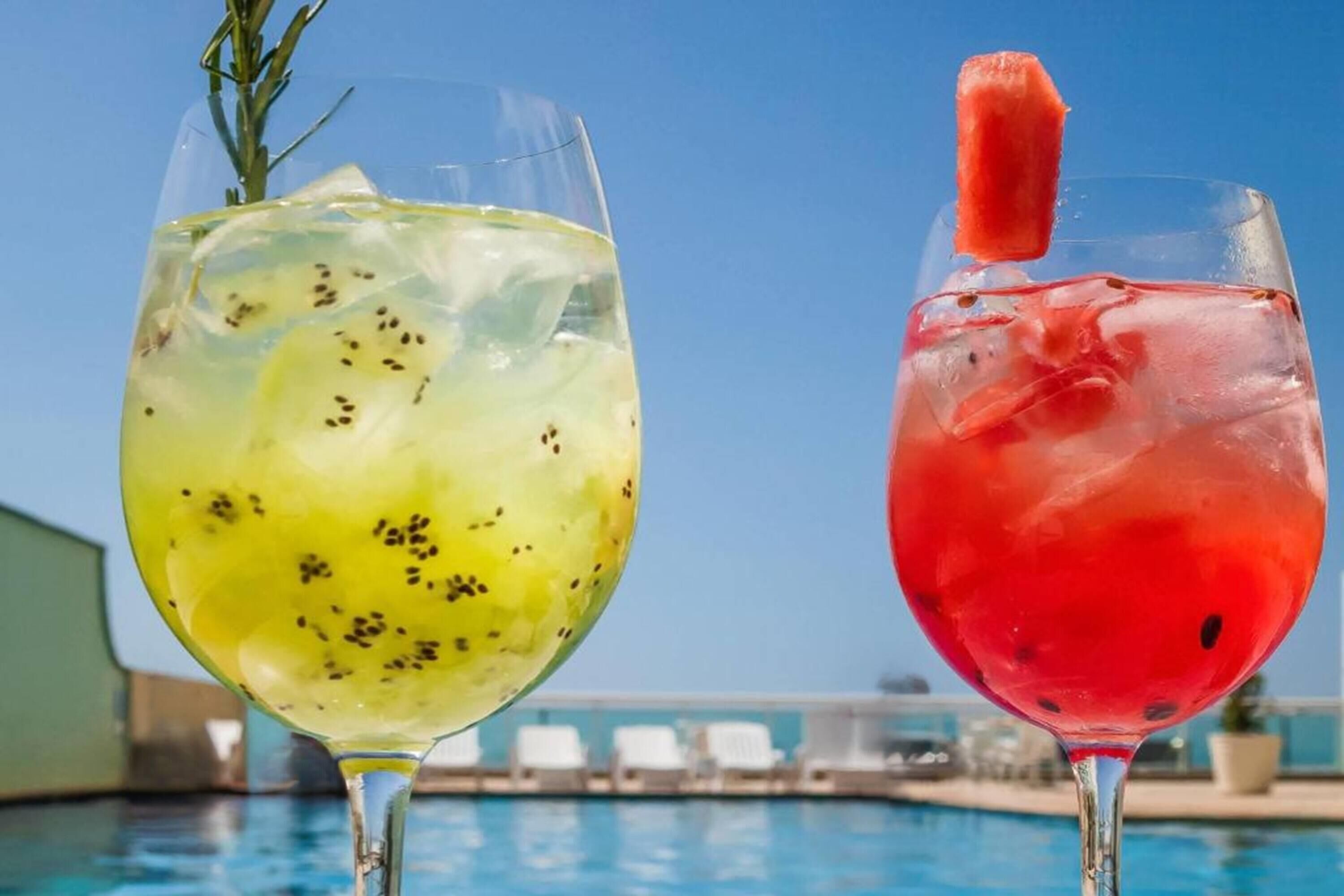 Two cocktails with a pool in the background.