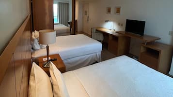 Une chambre d’hôtel avec deux lits, un bureau, une télévision et une lampe.