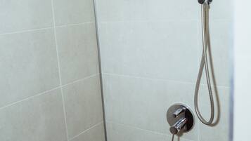 A shower with a handheld showerhead and a fixed showerhead, both mounted on a tiled wall.