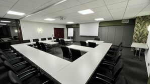 A conference room with a long table, multiple chairs, a whiteboard, and a projector. - Hotel Garni Geisler (Cologne)