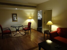 A cozy living room with a round table, two red chairs, a red sofa, and two lamps.