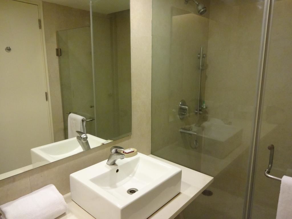 A modern bathroom with a white sink, a glass shower enclosure, and a large mirror.