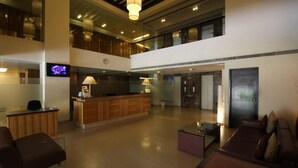A spacious lobby with a reception desk, seating area, and a staircase leading to an upper level. - Minerva Grand Secunderabad (Hyderabad)