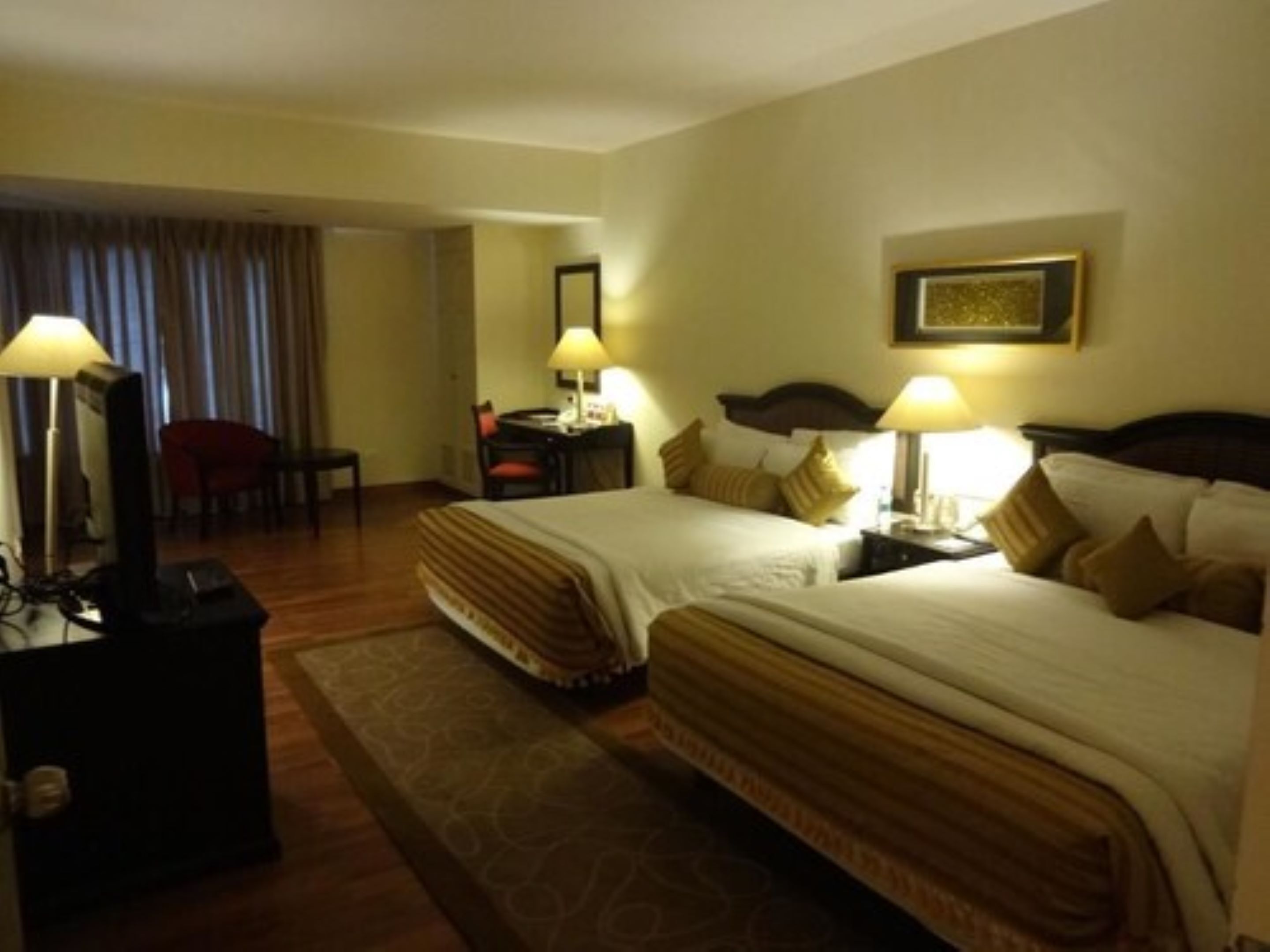 Una habitación de hotel con dos camas, un escritorio, una silla y una lámpara.