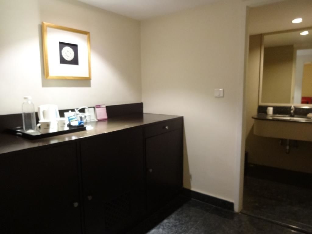 A hotel bathroom with a dark counter, a framed picture on the wall, and a mirror above the sink.