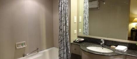 A modern bathroom with a bathtub, a sink, and a large mirror.