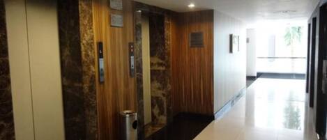 Un pasillo con ascensores y un contenedor de basura.