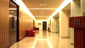 A hotel corridor with wooden paneling, a red seating area, and a reception desk. - Minerva Grand Secunderabad (Hyderabad)