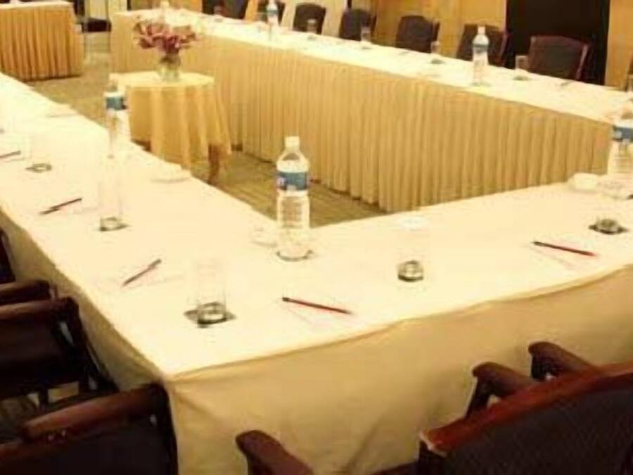 Un salón de conferencias con una larga mesa, sillas y botellas de agua.