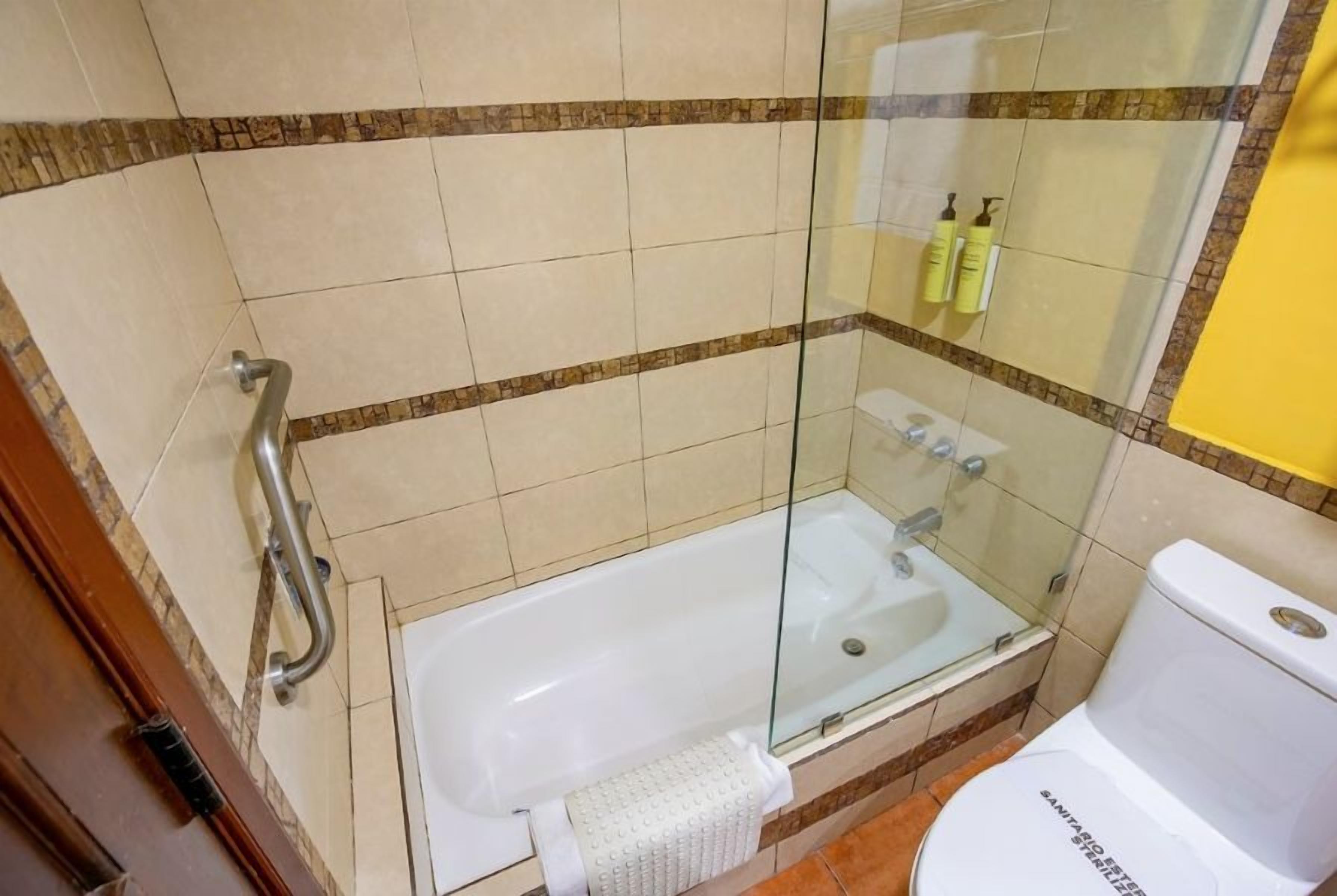 Un baño con ducha envuelta en vidrio, una bañera blanca y un inodoro.