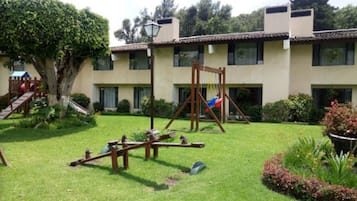 A courtyard with a swing set, a seesaw, and a small play structure.