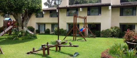 A courtyard with a swing set, a seesaw, and a small play structure.