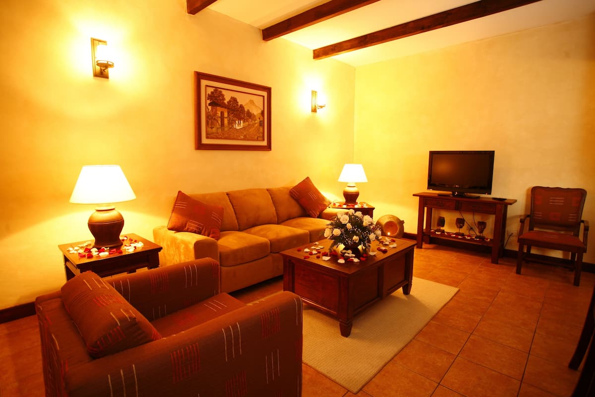 A cozy living room with a sofa, two armchairs, a coffee table, a television, and two lamps.