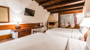 Habitación de hotel con dos camas, una televisión de pantalla plana, chimenea y techo de madera.