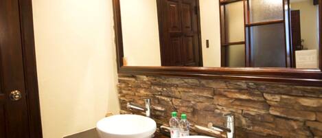 A bathroom with a stone accent wall, a white sink, and a mirror above it.