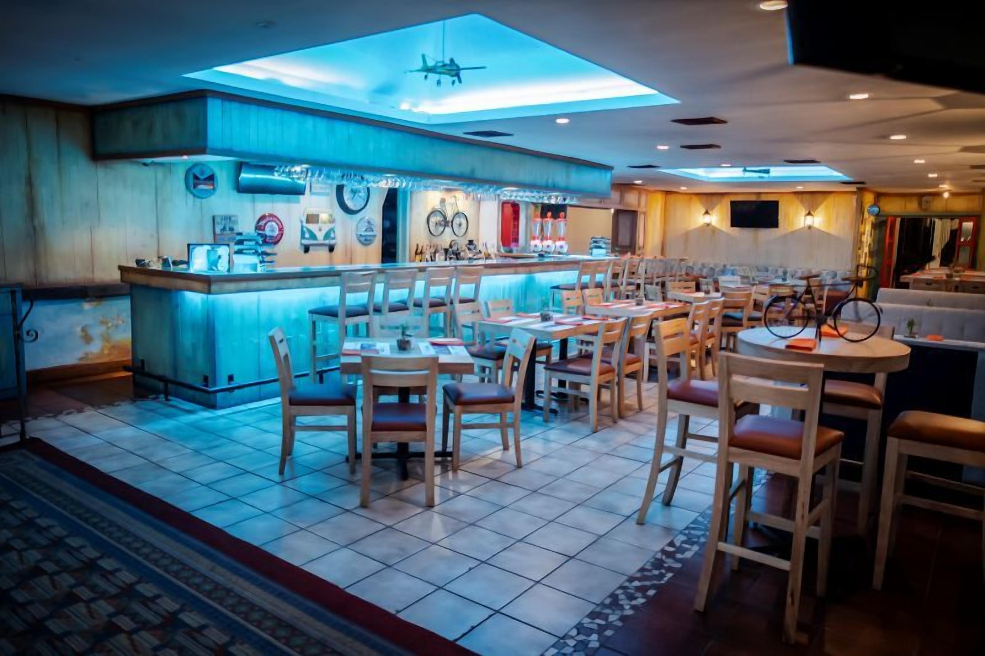 A restaurant with a bar area, multiple tables, and chairs.