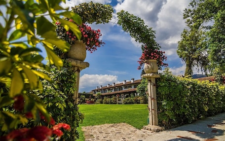 A garden pathway leading to a building with a green lawn and a clear blue sky.