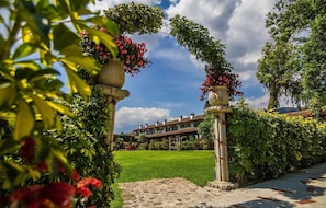 A garden pathway leading to a building with a green lawn and a clear blue sky.