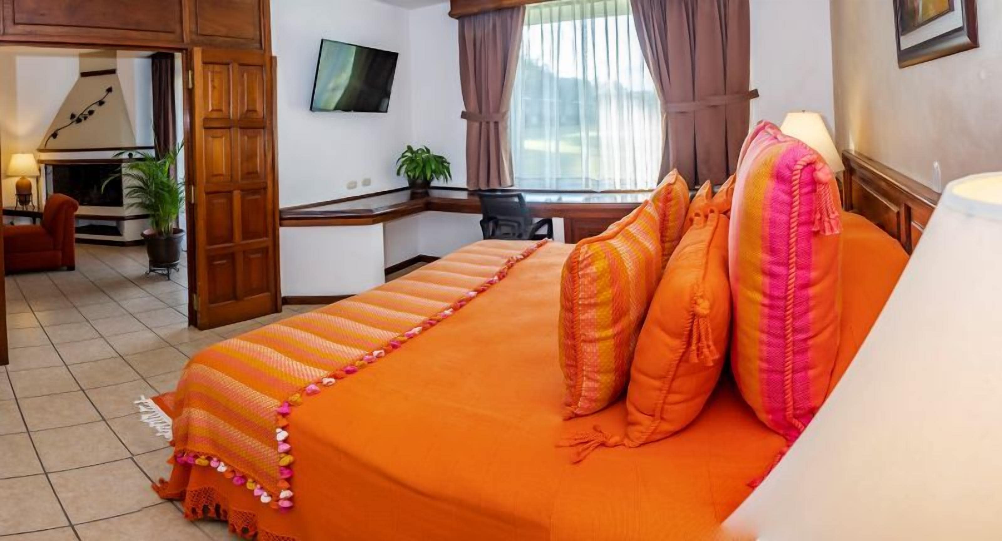 Une chambre d’hôtel équipée d’un lit, d’un bureau, d’une télévision et offrant une vue sur l’extérieur.