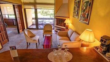 Habitación de hotel con sofá, sillas, una mesa de centro y una mesa de comedor con lámpara.
