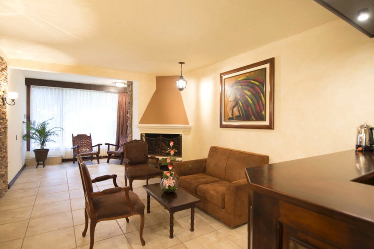 Una sala de estar con chimenea, sofá, sillones y una mesa de centro.