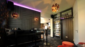 A bar area with seating, a bar counter, and a wall of liquor bottles. - Hotel zur Heidebluete (Hambuehren)