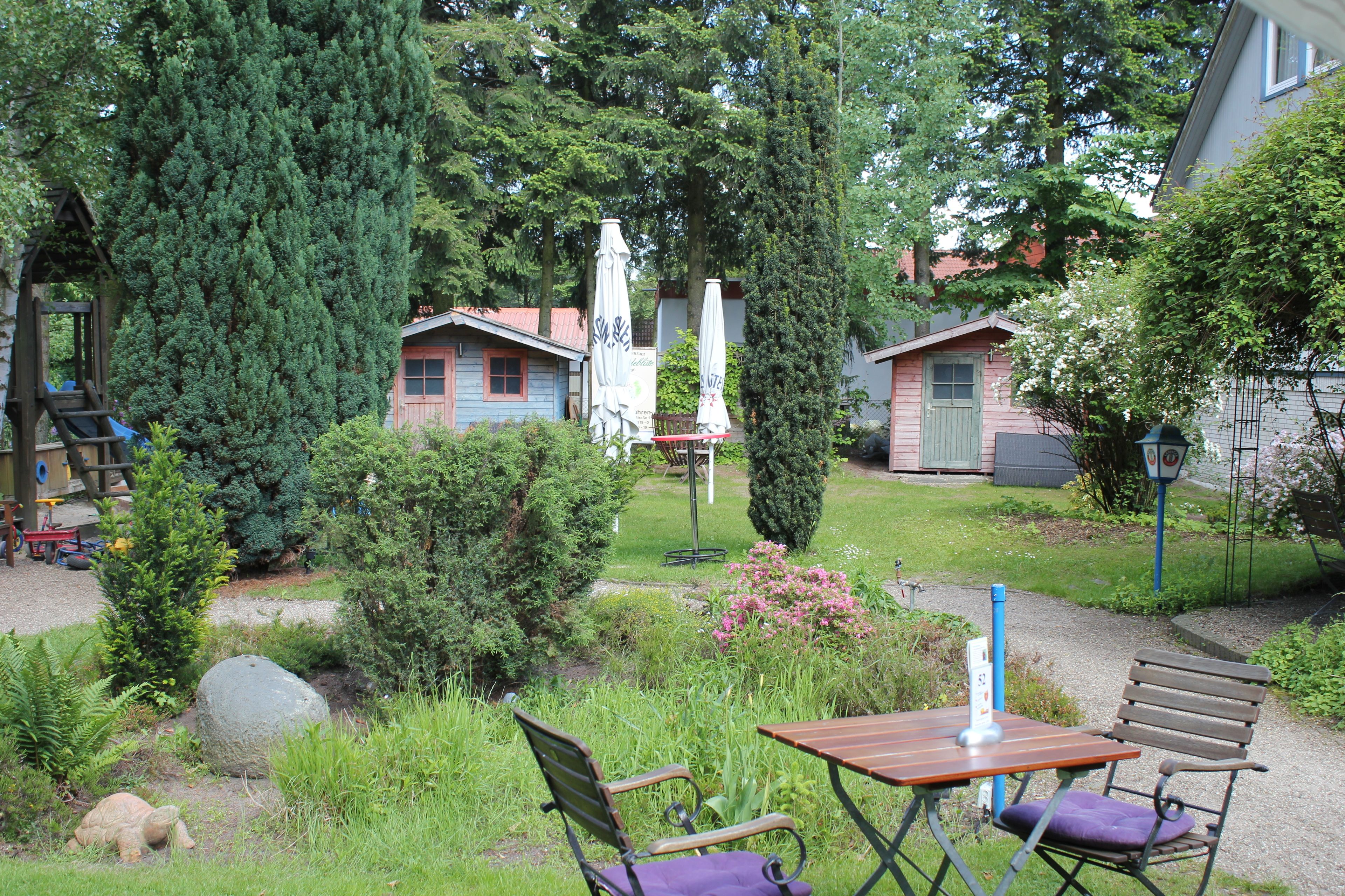 A garden area with outdoor seating, a playground, and two small buildings with a red roof.
