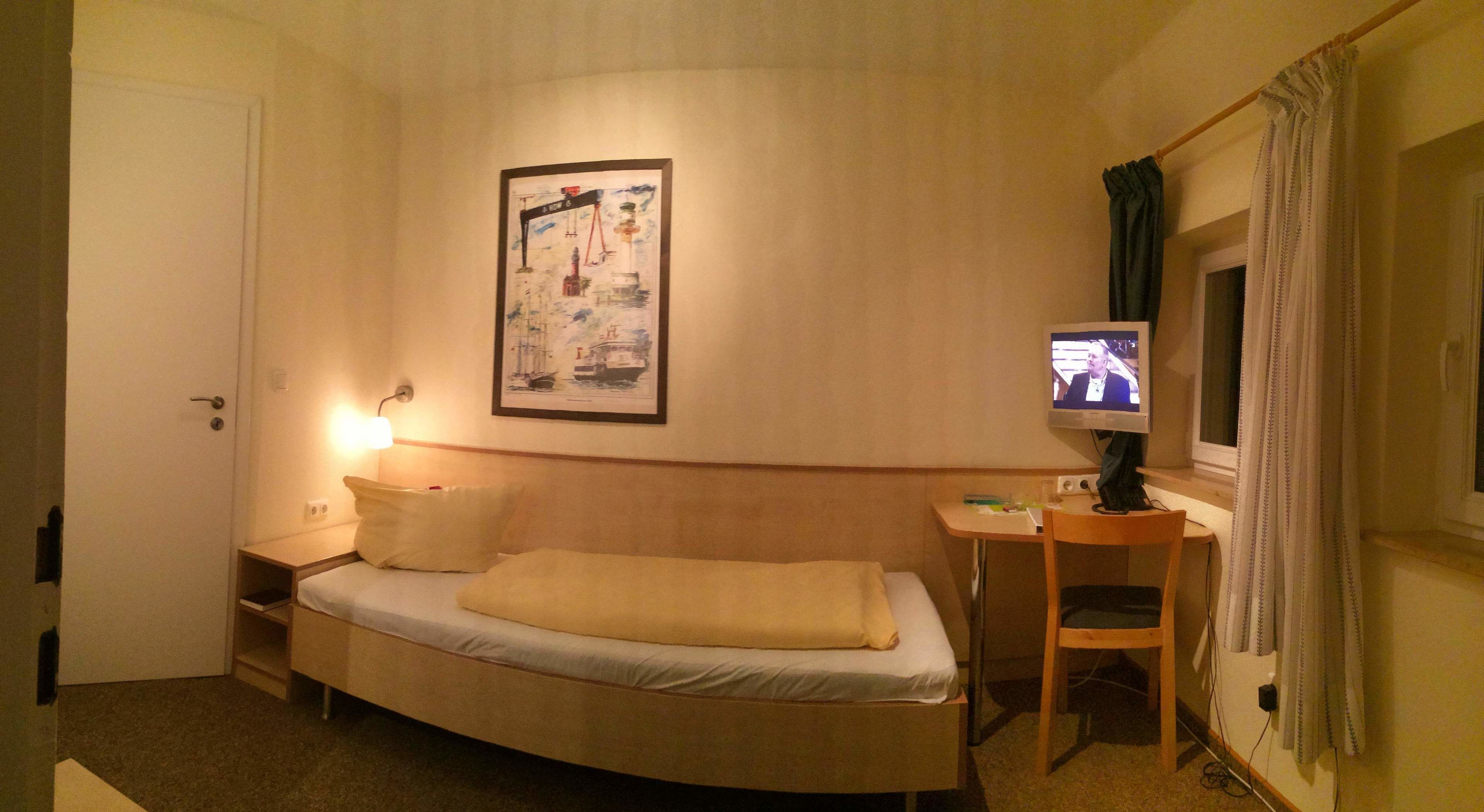 Une chambre d’hôtel avec un lit, un bureau, une télévision et un tableau encadré au mur.