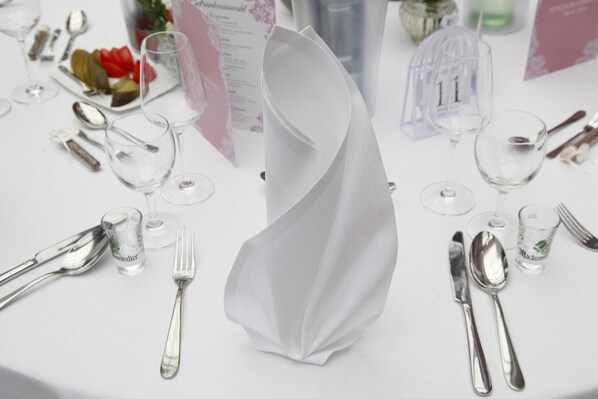 Una mesa dispuesta con cubiertos, una copa y un sujetavasos.