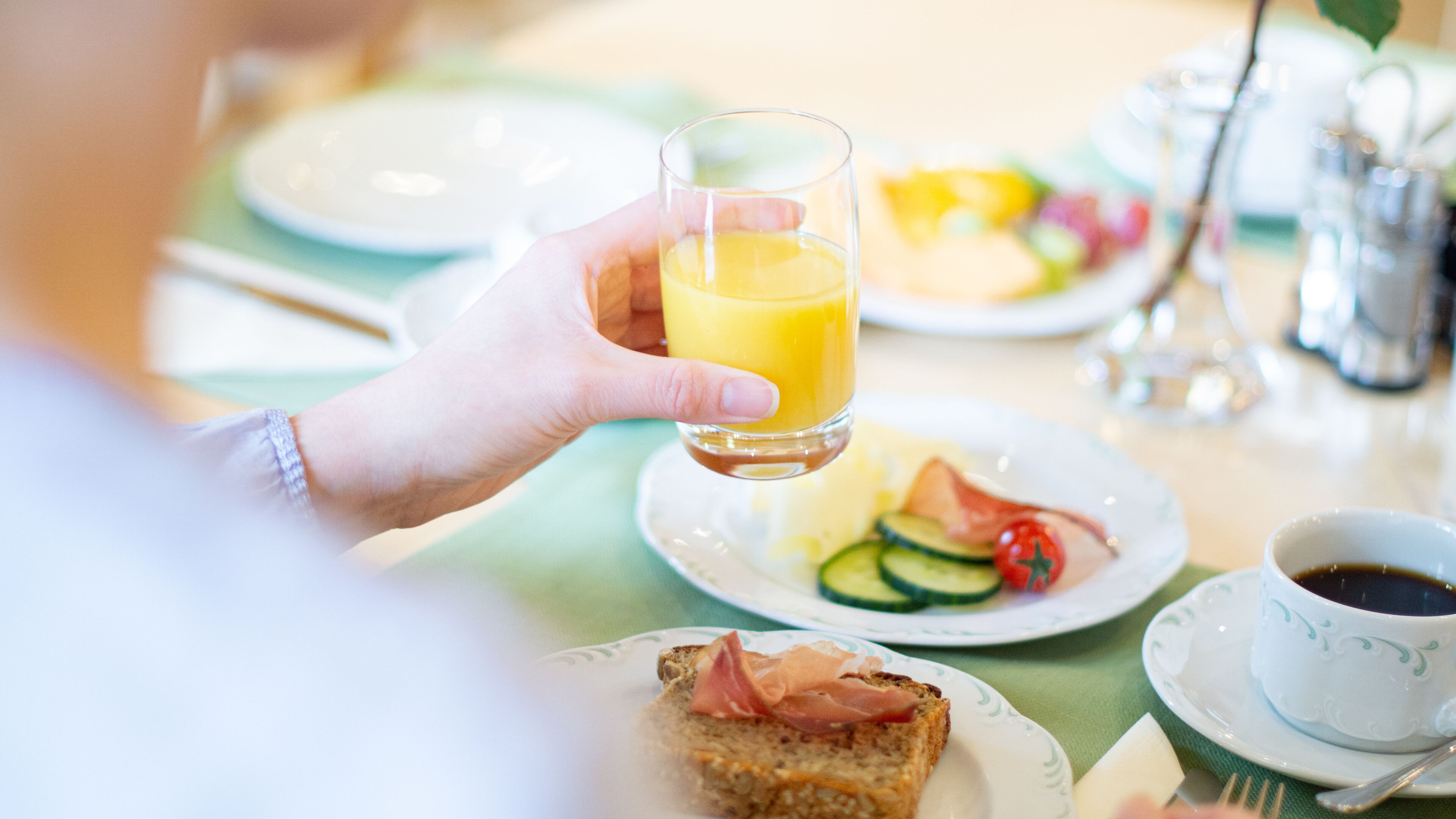A breakfast setting with a plate of food, a glass of orange juice, and a cup of coffee.