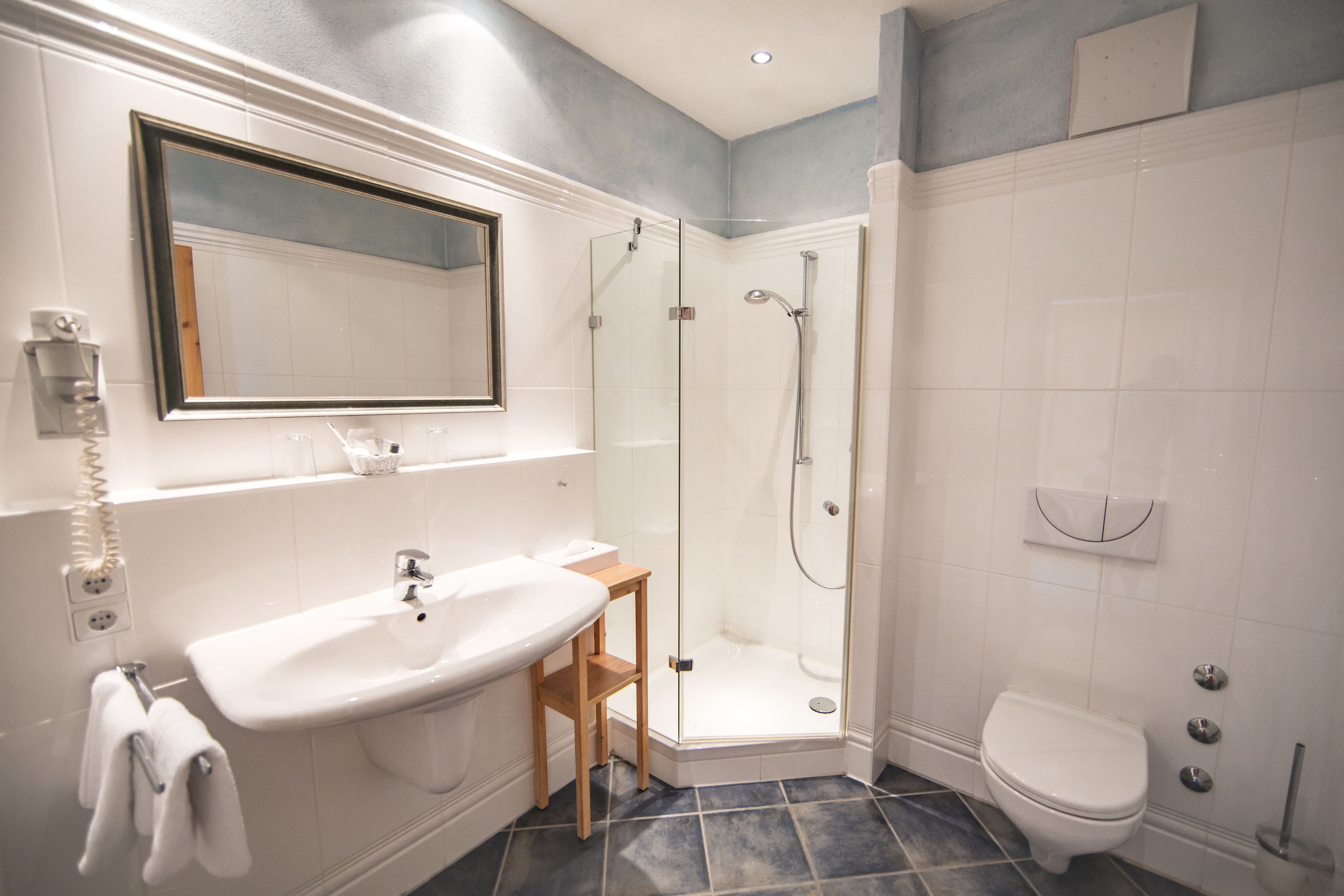Un baño moderno con lavamanos, espejo, ducha e inodoro.